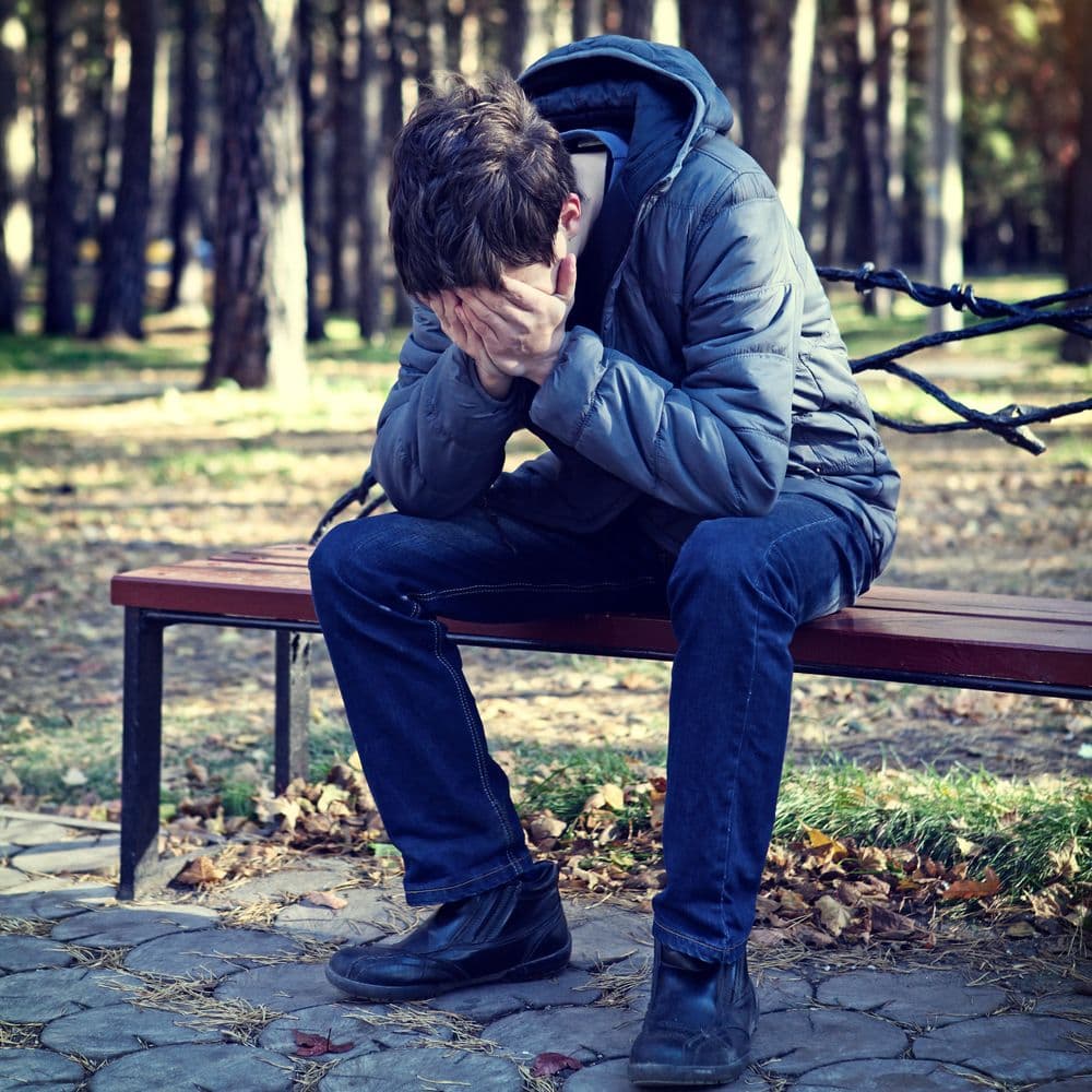 Garçon triste, se tenant le visage avec les mains